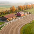 Tilt-shift miniature of a small country harness track in autumn with a clubhouse, a red barn and stables